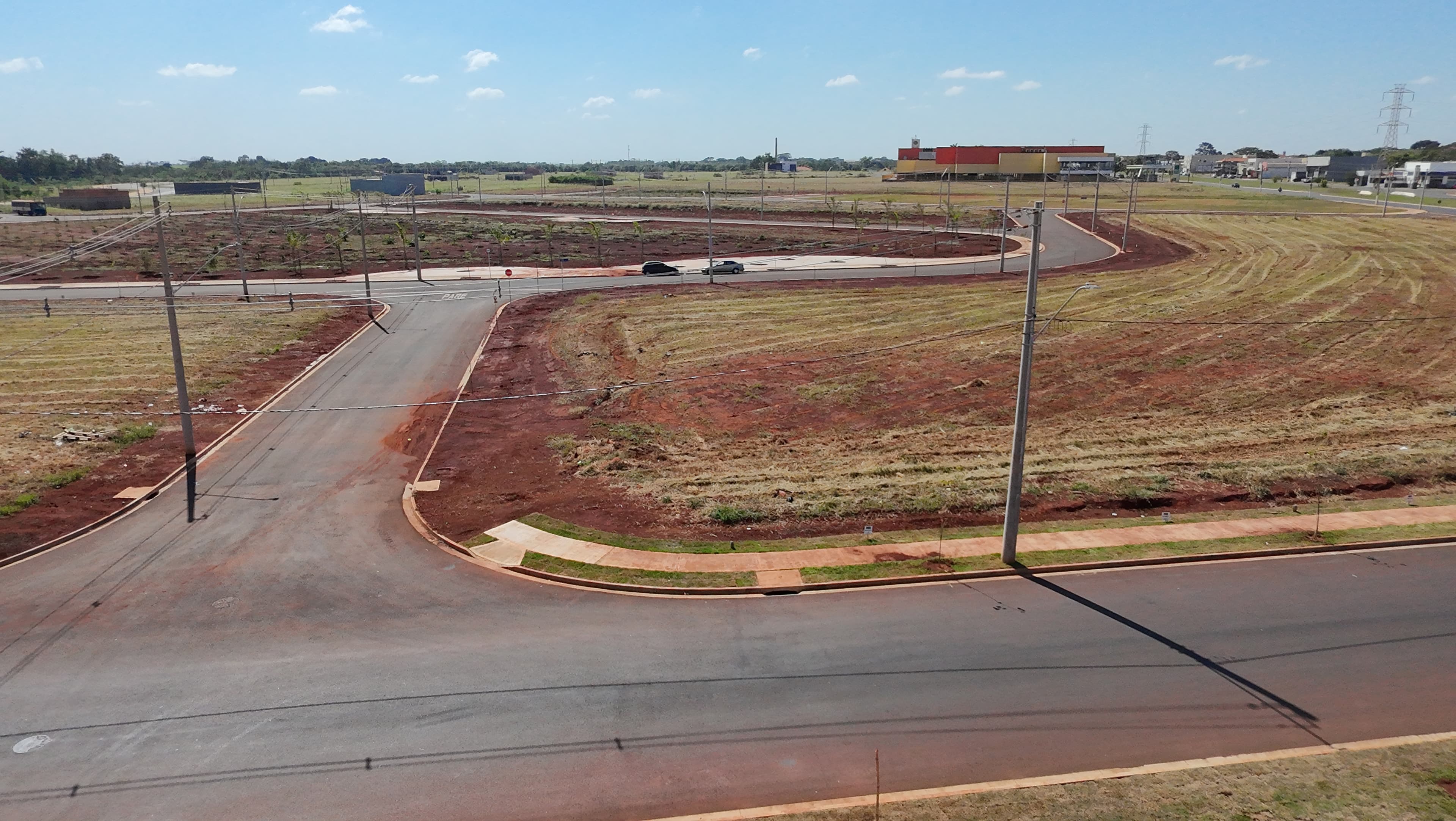Vista aérea do Bella Verona Boulevard em Maio de 2026, com ruas asfaltadas, postes de energia e terrenos nivelados com terra vermelha