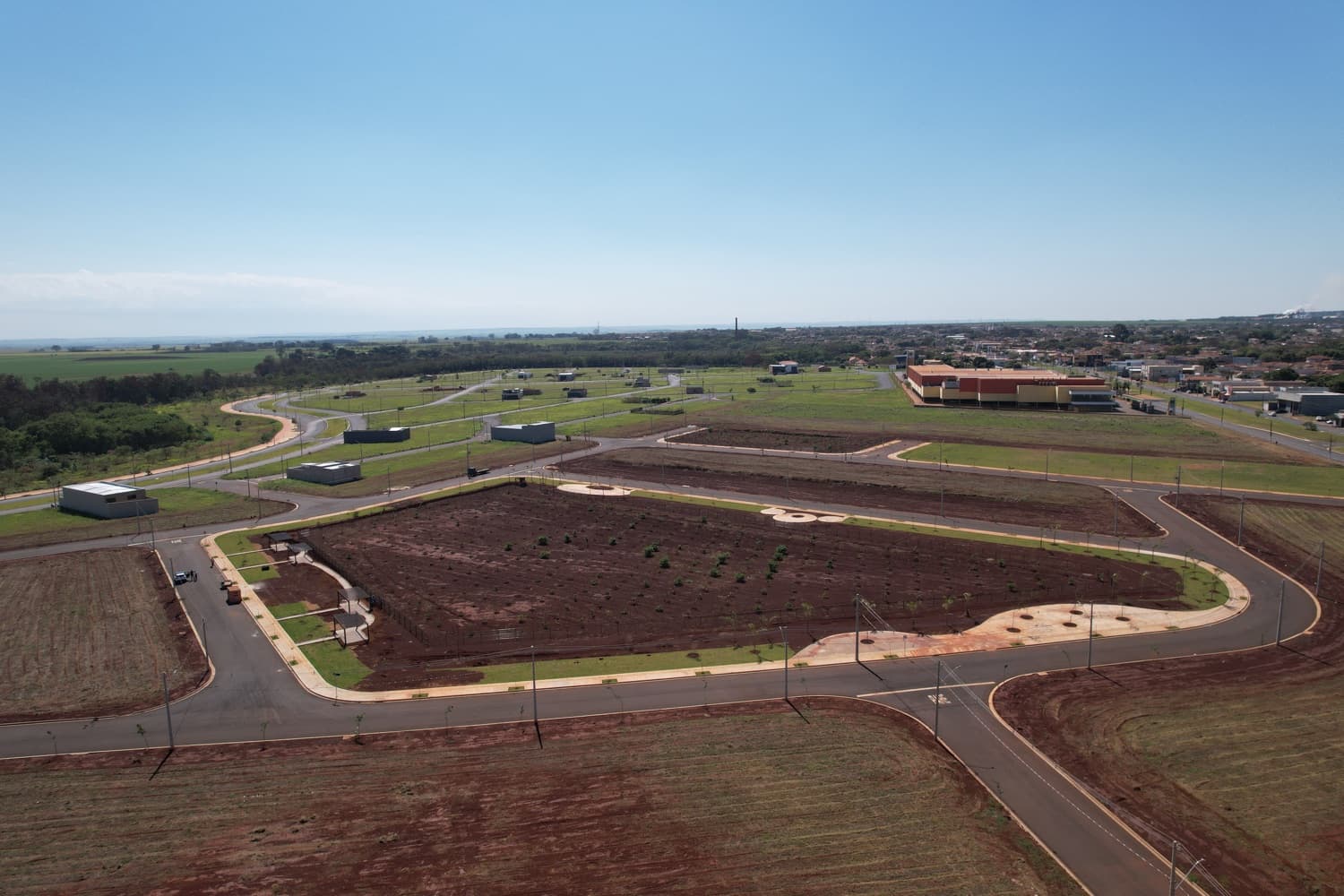 Vista aérea do Bella Verona Boulevard em Setembro de 2026, com avenidas pavimentadas, paisagismo e edifício comercial ao fundo